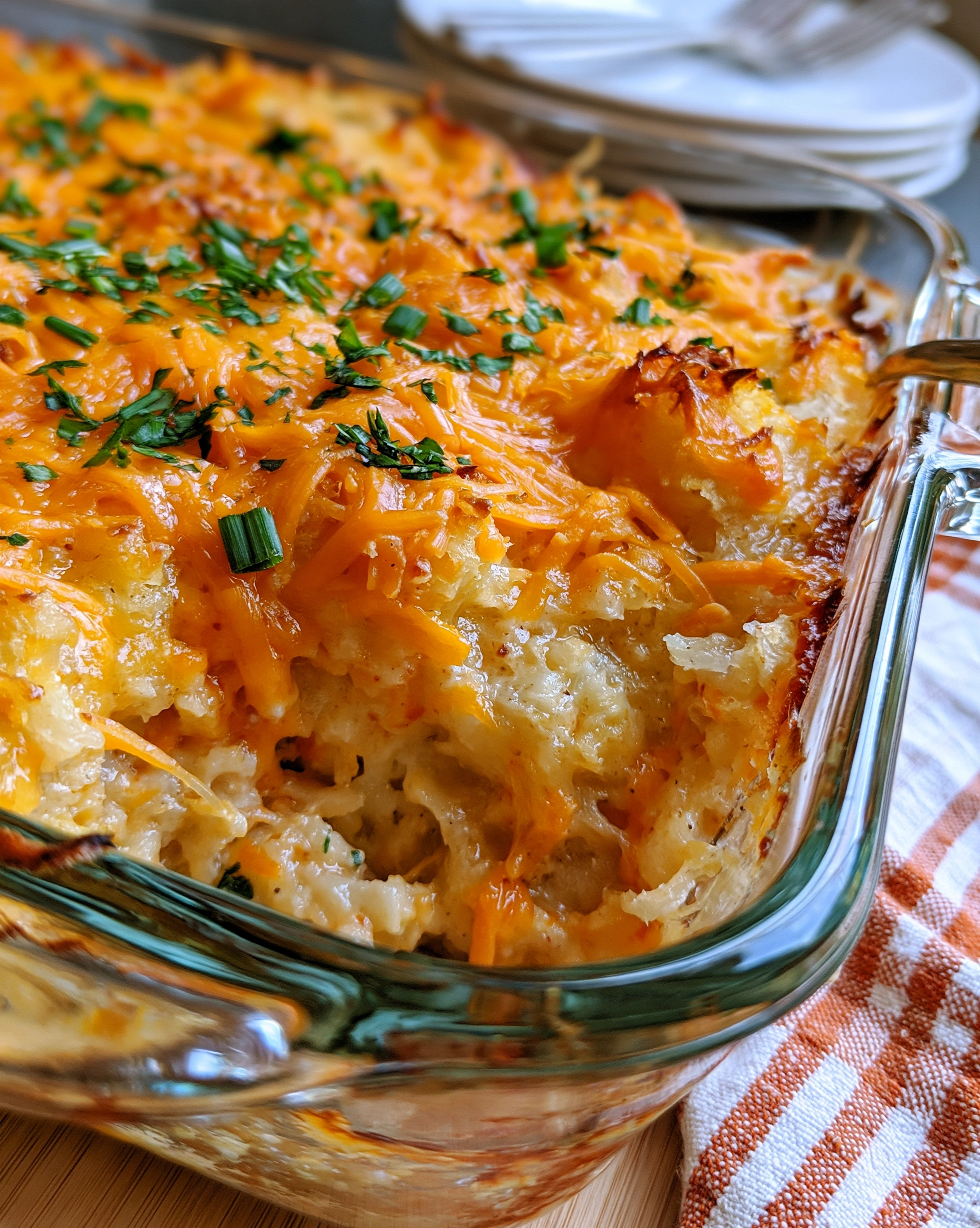 Easy cracker barrel hashbrown casserole recipe in a glass baking dish — creamy shredded potatoes under a golden melted cheddar top with chopped fresh parsley